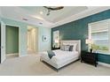 Main bedroom with tray ceiling, accent wall, ceiling fan, and access to a hallway with ensuite bathroom at 716 Manns Harbor Dr, Apollo Beach, FL 33572