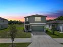 Charming two-story home with a well-manicured lawn and a two-car garage at sunset at 11530 Adam Lee Way, Dade City, FL 33525