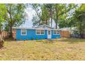 Charming blue home with stone accents, well-maintained lawn and mature trees at 1513 Escort Ave, Tampa, FL 33610