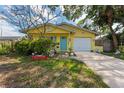 Charming yellow single-story home features a lovely blue front door and an attached one car garage at 1782 Maryland Ne Ave, St Petersburg, FL 33703