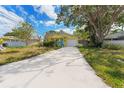 The front of this charming yellow home features a long driveway, mature landscaping, and attached single car garage at 1782 Maryland Ne Ave, St Petersburg, FL 33703