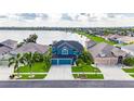 Aerial view of a blue home with three car garage next to a lake, lush landscaping, and neighborhood at 1806 Mira Lago Cir, Ruskin, FL 33570