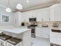 Modern kitchen with white cabinetry, stainless steel appliances, granite countertops, and stylish pendant lighting at 19337 Weymouth Dr, Land O Lakes, FL 34638