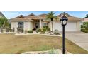 Inviting single-story home featuring a tile roof, two-car garage, manicured lawn, and mature palm trees at 2017 S Pebble Beach Blvd, Sun City Center, FL 33573
