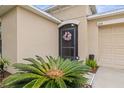 A closer view of the front door with a pretty wreath, adjacent to well-kept landscaping at 233 Cascade Bend Dr, Ruskin, FL 33570