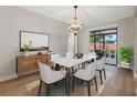 Bright dining room with modern chandelier, marble table, stylish chairs, and sliding glass doors to outdoor space at 2719 Cypress Hollow Ct, New Port Richey, FL 34655