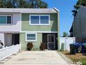 Exterior of a townhouse featuring a green facade, trimmed windows, and a concrete driveway at 2751 S Pines Dr # 10, Largo, FL 33771
