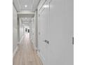 Well-lit hallway with wood-look floors, recessed lighting, and neatly lined white doors at 455 Pinellas Bayway S # 4A, Tierra Verde, FL 33715