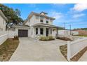 View of the home's side exterior, featuring an attached garage, driveway, and white picket fence at 5501 N 15Th St, Tampa, FL 33610