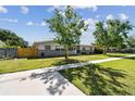 Single-story home showing the walkway and front yard with a tree casting shadows at 5601 16Th N St, St Petersburg, FL 33703