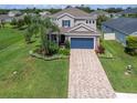 Two-story home featuring a well-manicured lawn, complemented by a brick driveway and a blue garage door at 879 De Soto Blvd, Tarpon Springs, FL 34689