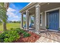 Inviting front porch with columns, a blue front door, and well-maintained landscaping at 879 De Soto Blvd, Tarpon Springs, FL 34689
