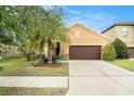 Charming single-Gathering home featuring a well-manicured lawn and a two-car garage with a lovely palm tree at 11818 Valhalla Woods Dr, Riverview, FL 33579