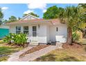 Front exterior view of a well-maintained home with tropical landscape and inviting pathway at 1232 Sedeeva S Cir, Clearwater, FL 33755