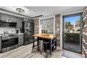 Modern kitchen featuring gray cabinetry, stainless steel appliances, and a central wooden island with seating at 135 Nina Way # 35, Oldsmar, FL 34677