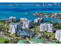 An aerial view of a condo community overlooking Sarasota Bay with other luxurious homes and clear blue water at 145 Belleview Blvd # 201, Belleair, FL 33756