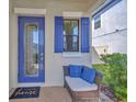 Cozy entryway with a decorative blue door, shutters, and a wicker chair at 1476 Fort Cobb Ter, Wesley Chapel, FL 33543