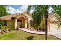 Charming single-Gathering home featuring a well-manicured lawn, a red brick walkway, and a tan exterior at 209 Arlington E Ave, Oldsmar, FL 34677