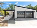 Home exterior features a modern design with a black garage door, white siding, and a covered front porch at 2257 Lake Dr, Dunedin, FL 34698