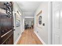 Bright hallway with hardwood floors, decorative mirror and artwork lead into the dining and living space at 2257 Lake Dr, Dunedin, FL 34698