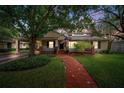 Inviting home with a charming brick pathway, lush landscaping, and a cozy front porch at dusk at 3408 W San Jose St, Tampa, FL 33629