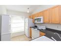 Kitchen featuring light cabinetry, white appliances, and a large window for natural light at 3777 Mission Ct, Largo, FL 33771