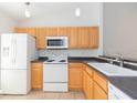 Bright kitchen featuring light wood cabinets, white appliances, and ample counter space at 3777 Mission Ct, Largo, FL 33771