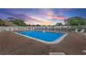 Community swimming pool surrounded by a white fence and lounge chairs; perfect for relaxing on warm days under a colorful sky at 6490 Cape Hatteras Ne Way # 4, St Petersburg, FL 33702