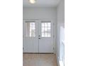 Entryway features a glass front door and tan tile flooring, with natural light streaming through at 7647 Navigator Ct, Port Richey, FL 34668