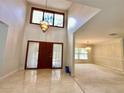 Bright foyer with high ceilings, a modern chandelier, tile flooring, and a dark wood front door at 10206 Lakeview Dr, New Port Richey, FL 34654