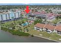 Aerial view of a condo building with pool, palm trees, and waterfront access, highlighting community amenities at 10215 Regal Dr # 21, Largo, FL 33774