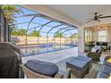 Covered patio next to a screened-in pool with lounge chairs and a waterfall feature at 11854 Lake Lucaya Dr, Riverview, FL 33579