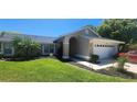 Well-maintained home featuring a two-car garage, manicured lawn, and lush landscaping at 14324 Bronte Ct, Hudson, FL 34667