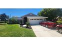 Charming single-story home boasts a manicured lawn, a two-car garage, and vehicles at 14324 Bronte Ct, Hudson, FL 34667
