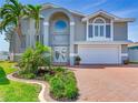 Elegant home with a spacious garage and a grand entrance framed by mature palm trees at 17382 Kennedy Dr, North Redington Beach, FL 33708