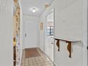 View of foyer with ceramic tiles, coat closet, and half-wall decorated with floral wallpaper at 1800 Mariner Dr # 2, Tarpon Springs, FL 34689