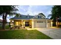 Charming home with a well-manicured lawn, beautiful landscaping, and illuminated exterior lights at 24314 Landing Dr, Lutz, FL 33559