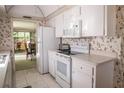Bright kitchen features white cabinets, appliances, and unique strawberry wallpaper at 2630 Pearce Dr # 104, Clearwater, FL 33764