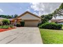 Exterior view of a one-story home with a two-car garage and a lush green lawn at 3310 Tanglewood Trl, Palm Harbor, FL 34685