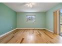 Empty bedroom showcases hardwood floors, light green walls, a window, and a sliding glass door at 4801 Airport Rd # 214, Zephyrhills, FL 33542