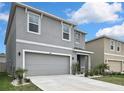 Two story home with gray stucco exterior, light landscaping, and an attached two car garage at 5602 Wandering Willow Dr, Wesley Chapel, FL 33545