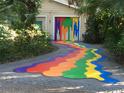 Unique driveway and garage with eye-catching rainbow paint design, creating a fun and vibrant entrance at 6014 Luana S Ln, Gulfport, FL 33707