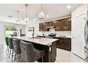 Modern kitchen featuring dark wood cabinetry, quartz countertops, and elegant pendant lighting at 6700 Devlin Ln, Wesley Chapel, FL 33545