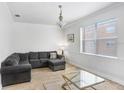 Light-filled living room with wood floors, neutral paint and comfortable sectional sofa with ottoman at 6823 S Kissimmee St, Tampa, FL 33616