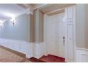 Hallway view of a unit entrance featuring classic wainscoting, neutral paint, and modern lighting at 7903 Seminole Blvd # 2103, Seminole, FL 33772