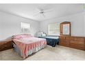 Bright bedroom featuring two beds, neutral carpet, a ceiling fan, and natural light from a large window at 9069 Gaynor St, Spring Hill, FL 34608