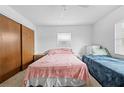 Bright bedroom featuring two beds, neutral carpet, a ceiling fan, and natural light from a large window at 9069 Gaynor St, Spring Hill, FL 34608