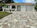 Beautiful house featuring a brick driveway, arched doorway, white stucco, and lush landscaping for inviting curb appeal at 11241 Temple Ct, Seminole, FL 33772