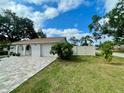 Single-story home with a brick driveway, white stucco exterior, attached garage, and a spacious, well-manicured lawn at 11241 Temple Ct, Seminole, FL 33772