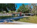 Well-maintained house with a brick chimney, cozy carport, and neatly manicured lawn at 13116 N Oregon Ave, Tampa, FL 33612